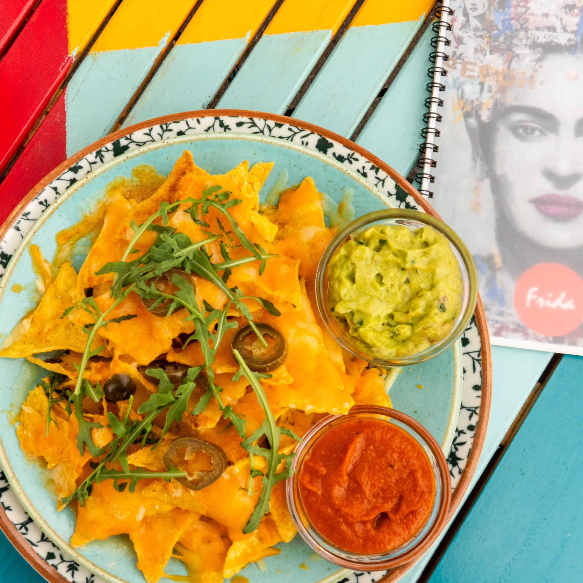 Nachos mit Guacamole und Dips auf dem bunten Tisch im Schanigarten