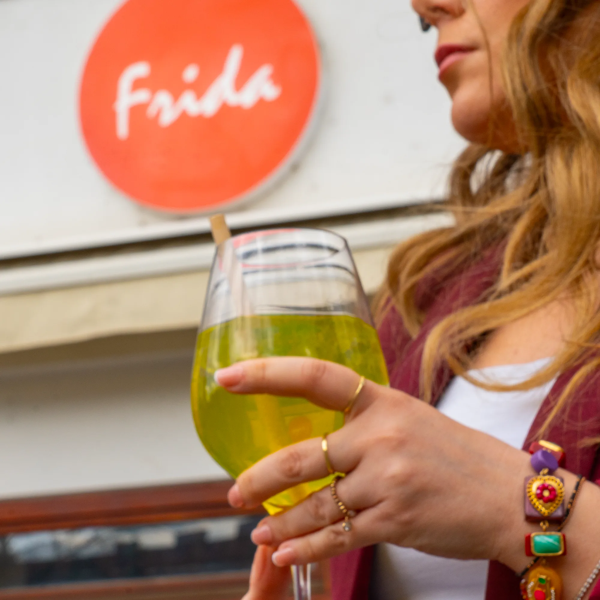 Drink in der Hand vor dem roten Frida-Logo an der Fassade in der Payergasse