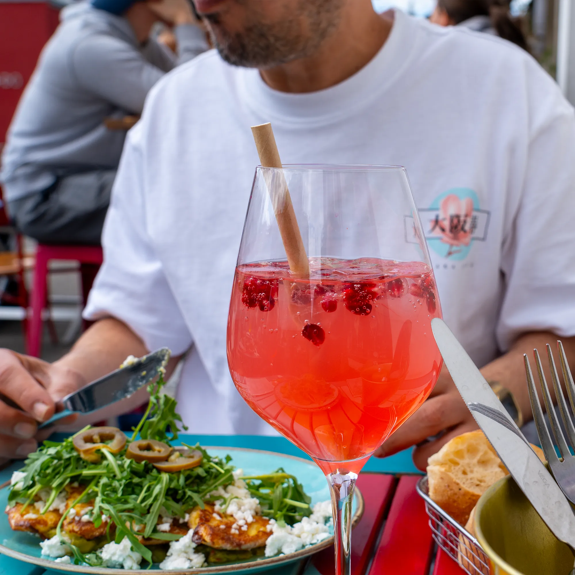 Aperol Spritz und ein Teller mit Rucola auf dem bunten Tisch im Schanigarten des Café Frida am Yppenplatz