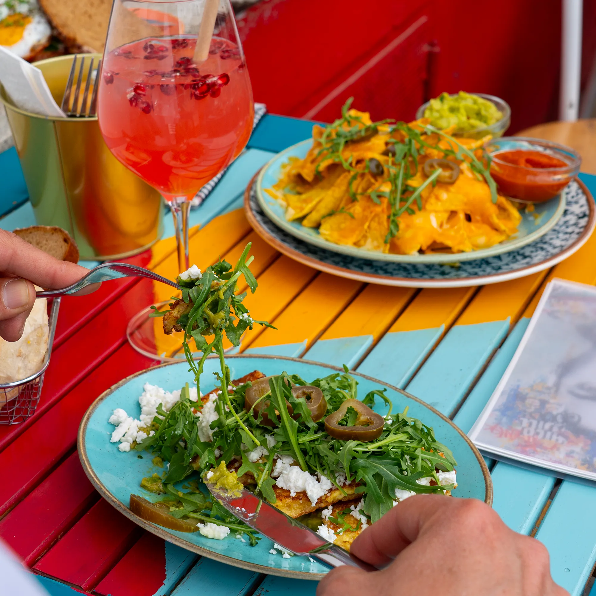 Teller mit Rucola, Ofengemüse und Nachos auf dem türkisen Tisch im Café Frida am Yppenplatz