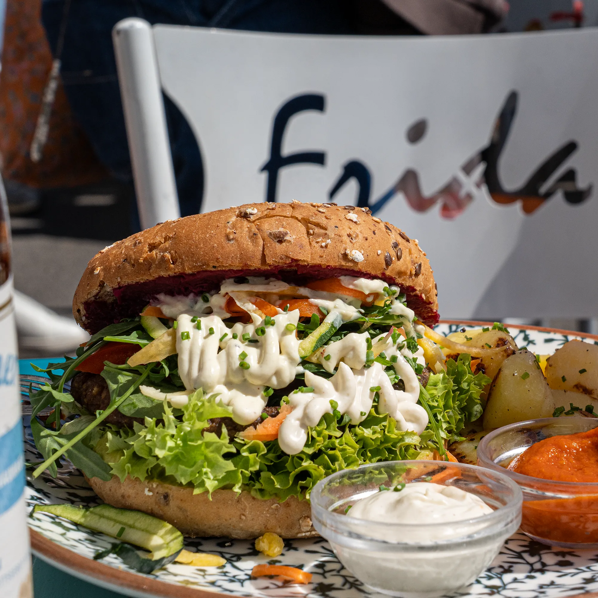 Burger vom Bio-Rind mit Salat und Dip vor dem Frida-Schriftzug, Café Frida Wien 1160